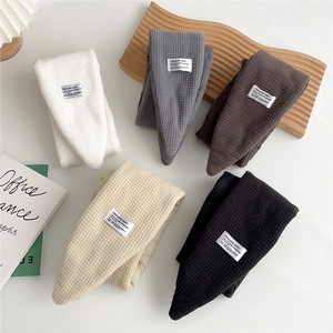 Flat lay of quilted down mufflers in white, grey, brown, beige, and black colors