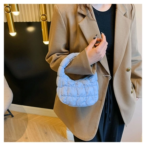 Close-up of a light blue quilted cloud bag showing mini size and puffy nylon texture