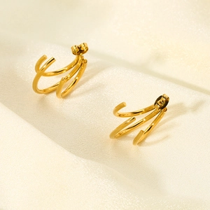 Détail de boucles d'oreilles en acier doré 18 carats avec triple motif en C superposé