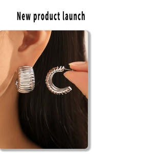 Macro shot of silver striped C-shape hoop earrings showing scale and detail on ear