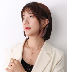 Modella indossa un set di gioielli d'oro con collana di cristalli, orecchini e anello