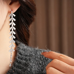 Detailed view of long leaf tassel earrings with baguette-cut zircons and silver needles