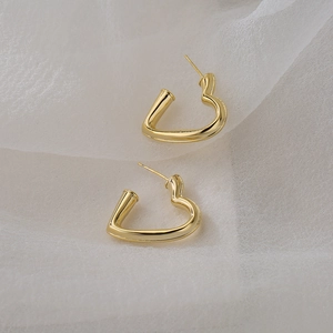Minimalist 18K gold plated heart hoop earrings for women on soft white fabric background