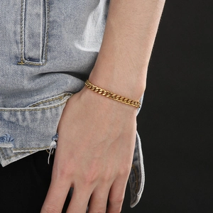 Detail of a gold Cuban chain bracelet on wrist featuring a classic lobster clasp