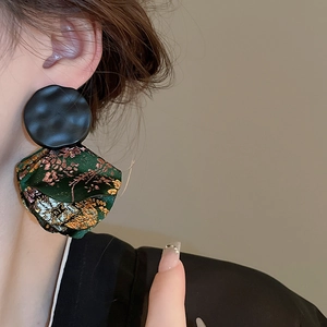 Detail of ethnic style hoop earring with gold floral brocade and black hammered metal