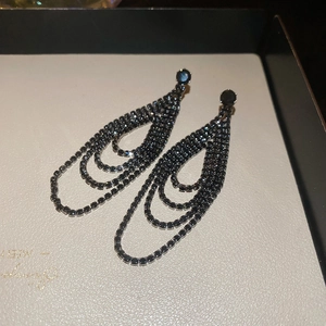 Détails macro des boucles d'oreilles à pompons noirs serties de strass scintillants