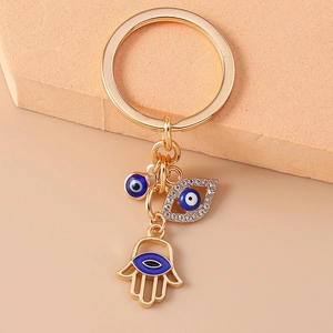 Detailed close-up of golden keychain featuring Hamsa hand and blue Evil Eye charms