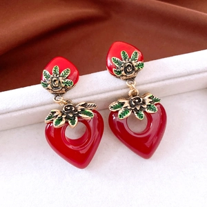 Close-up of vintage heart earrings with red strawberry design and gold metal leaves