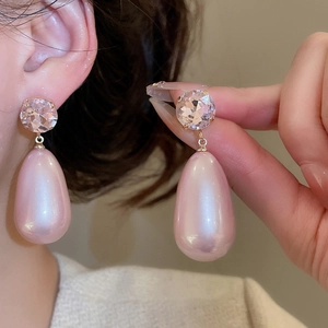 Detail of pink crystal teardrop earrings with faux pearls worn by a model