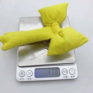 Lightweight bright yellow 3D ribbon bow keychain accessory weighing 11.8g on a scale