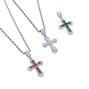 Detailed close-up of three hip hop cross pendants with orange, white and green zircon stones