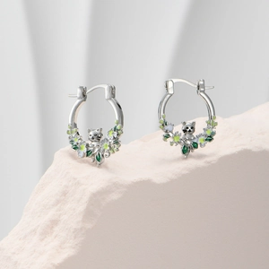 Detail of silver cat earrings with green and white enamel flowers on stone base