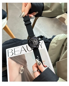 Close-up of black multi-dial quartz watch with silicone strap against a magazine backdrop