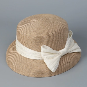 Dettaglio del cappello di paglia kaki con fiocco bianco a pieghe e trama di tessitura elegante