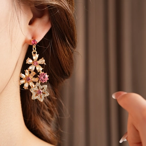 Detail of vintage flower earrings with gold finish and pink crystal stones on model