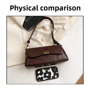 Draufsicht einer dunkelbraunen matten Leder-Achseltasche mit Gold-Schnalle auf einem Blazer