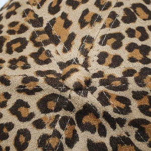 Primer plano macro del botón superior y la textura de leopardo de una gorra de béisbol