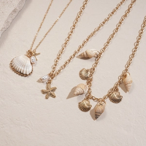 Détail d'un ensemble de trois colliers dorés avec coquillages, étoiles de mer et perles