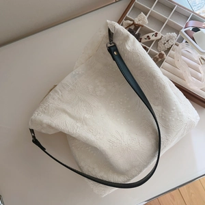 Close-up of floral embroidery on cotton canvas tote with black leather strap buckle