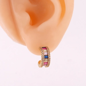 Close-up of C-shaped gold hoop earrings with multi-color rhinestones worn by a model