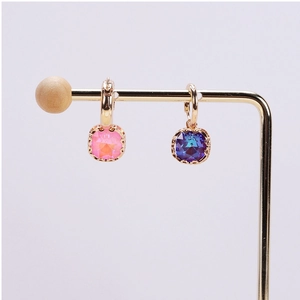 Close-up of pink and purple square crystal pendants set in golden claw metal frames
