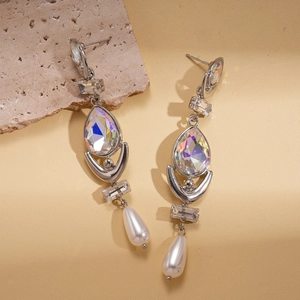 Silver drop earrings featuring iridescent crystals and pear-shaped pearls on beige leather