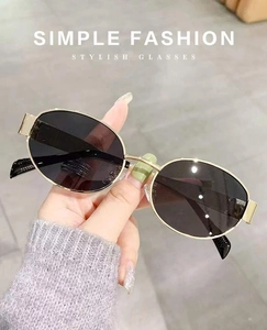 Detail of oval sunglasses with gold metal frame and dark gray polarized lenses