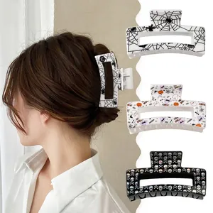 Three Halloween hair claws featuring spider webs, ghosts, and colorful skulls for styling