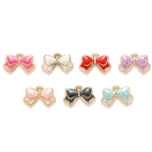 Set of seven colorful enamel bowknot charms in alloy with gold trim on white background