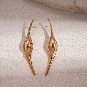 Detailed view of irregular curved gold geometric earrings on elegant marble and stone