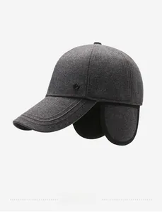 Detail view of dark grey winter earflap hat with thick wool texture and metal logo buckle