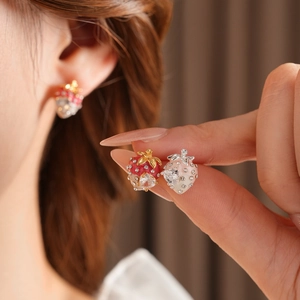 Macro view of strawberry earrings with red enamel, gold plating, and sparkling zircons