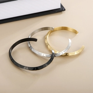 Detailed view of C-shaped titanium steel bangles with engraved geometric patterns in three colors