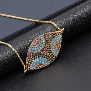 Macro shot of gold heart eye pendant necklace featuring vibrant multi-colored gemstones