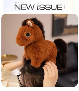 Detail of soft brown plush pony doll with black mane and golden star-shaped eye embroidery