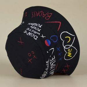 Detail of black canvas bucket hat with street style graffiti letters and heart patterns