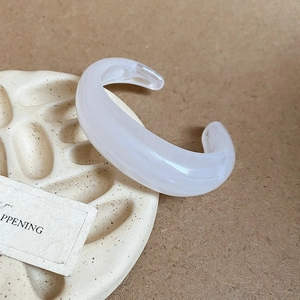 Macro detail of white marble acrylic cuff bracelet on ceramic tray with minimalist design