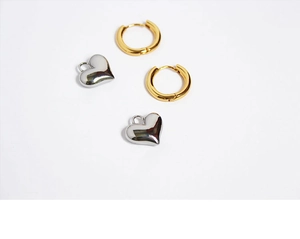 Macro shot of gold hoop earrings with silver heart pendants and shiny metallic finish