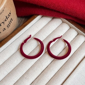 Detailed view of red velvet flocking hoop earrings on a beige jewelry display tray