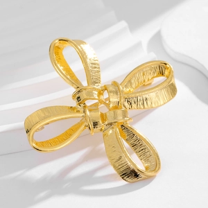 Vintage golden bow brooch with detailed metallic texture on a white background