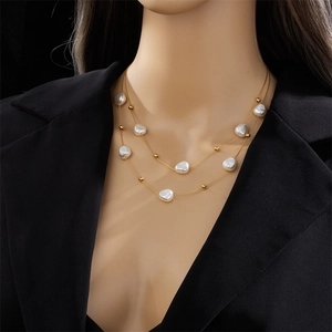 Double-layered gold titanium necklace with baroque pearls on model in black blazer