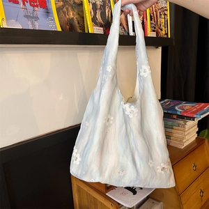 Detail of light blue tote bag with white flower embroidery in a home setting