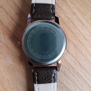 Macro shot of stainless steel watch back featuring AIMEINI logo and leather strap