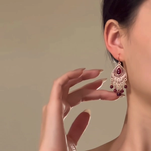 Gros plan de boucles d'oreilles vintage en forme de goutte rouge avec filigrane doré et perles