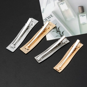 Detailed macro view of gold and silver rectangular metal hair clips with stripe patterns