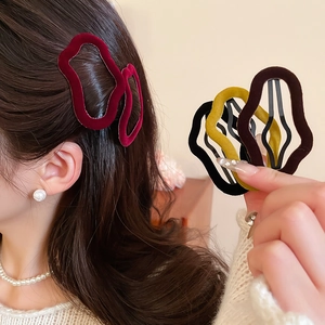 Close-up of irregular flocked velvet hair clips in deep red and warm autumnal colors