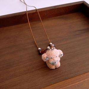 Chic plush poodle puppy pendant necklace with beaded strap on a wooden tray