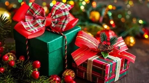 Close-up of festive Christmas gift boxes with pine cones and ribbons by a tree