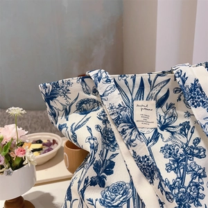 Detail of vintage blue floral patterns and woven label on a cream cotton tote bag