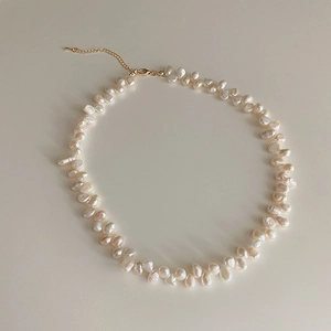 Detailed macro view of baroque freshwater pearls with golden lobster clasp and extension chain